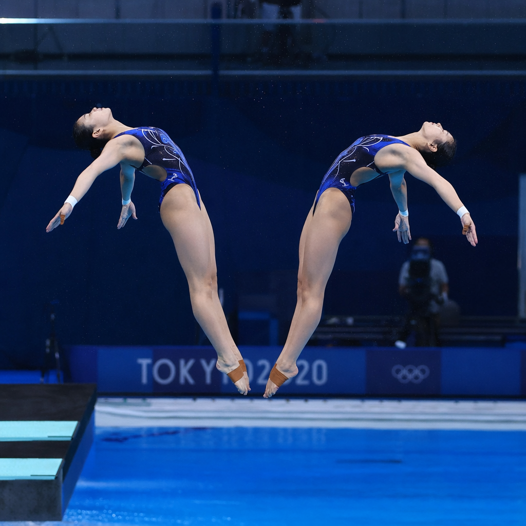 Two synchronized divers performing an artistic dive in perfect symmetry